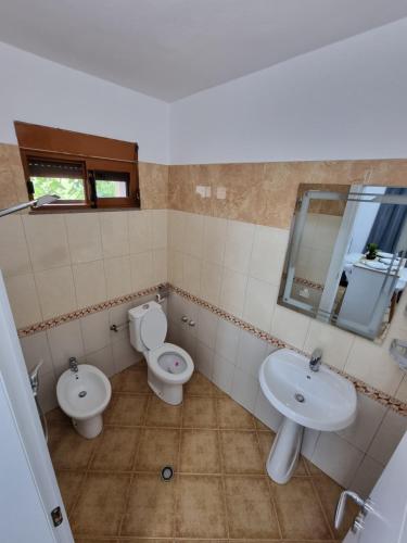 un bagno con due wc, un lavandino e uno specchio di Studio Vlora a Vlorë