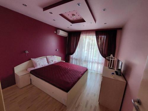 a bedroom with a bed with purple walls and a window at Apartment А13 in Sea Paradise Complex in Kavarna