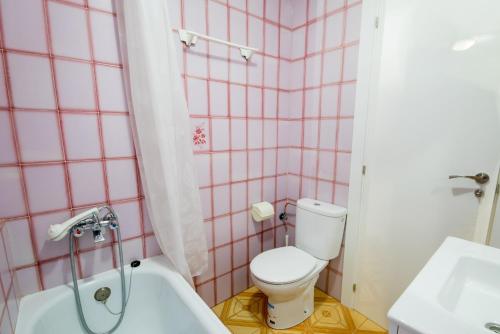 a pink tiled bathroom with a toilet and a bath tub at Apartamento Paco 3 cerca de Valencia in Benafer