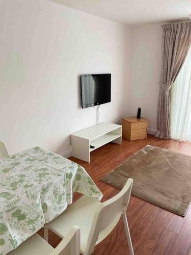 a white living room with a table and a tv at Modern 2 bedroom house with WIFI in Welwyn Garden City