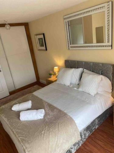 ein Schlafzimmer mit einem Bett mit zwei Kissen und einem Spiegel in der Unterkunft Modern 2 bedroom house with WIFI in Welwyn Garden City