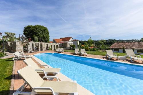 a swimming pool with lounge chairs and a house at Quinta Lusitânia in Santa Comba Dão
