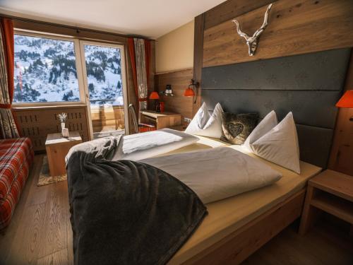 a bedroom with two beds and a large window at Hotel Kristall in Obertauern