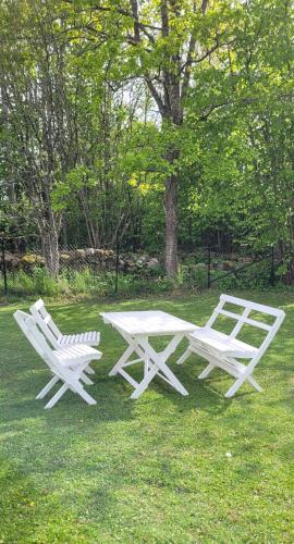 two white picnic tables and chairs in the grass at Fridfullt läge mitt på Öland in Färjestaden
