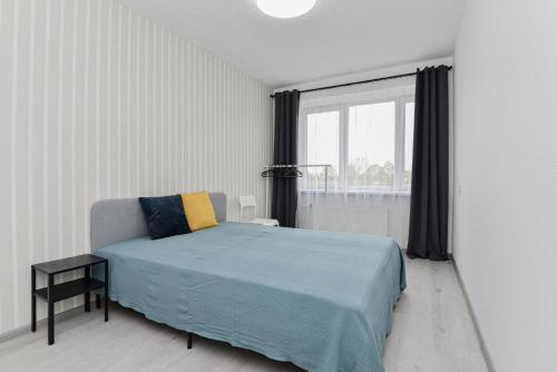 a white bedroom with a bed and a window at Big Petera in Ventspils