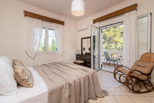 a bedroom with a bed and a chair and a balcony at Luxury Villa Vanato & Pool in Koukounariá