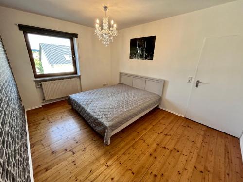 een slaapkamer met een bed, een raam en een kroonluchter bij Ferienwohnung am Staffelsberg in Bad Kissingen