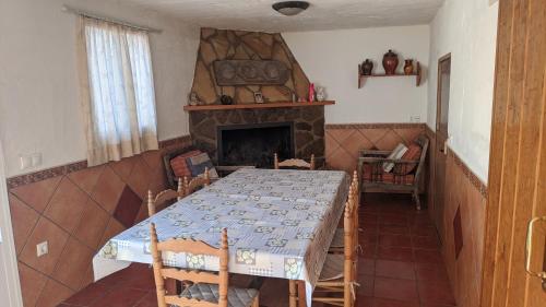 ein Esszimmer mit einem Tisch und einem Kamin in der Unterkunft Casa rústica de pueblo en Sierra de Alcaraz in Salobre