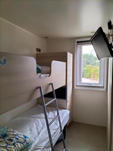 een kleine kamer met stapelbedden en een raam bij Camping in Le Muy