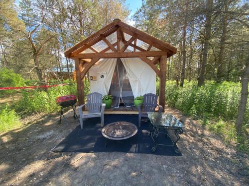 a tent with two chairs and a table and a grill at Dreamers Writing Farm, 3 Wooded Acres, Hepworth in Sauble Beach