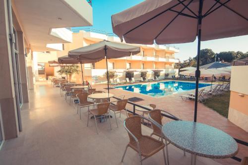 a patio with tables and chairs and a swimming pool at Adonis Hotel in Mitikas