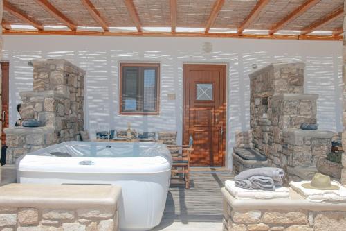 baño con bañera y pared de piedra en Granite Village Mykonos en Ano Mera