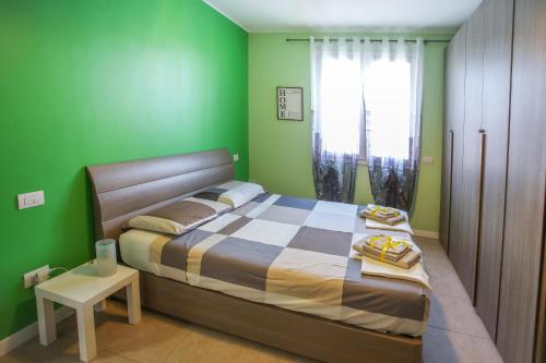 ein grünes Schlafzimmer mit einem Bett und einem Tisch in der Unterkunft Maison Emozioni in Limbiate