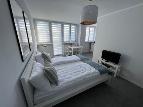 ein weißes Schlafzimmer mit einem Bett und einem TV in der Unterkunft APARTAMENT OŚ. JASNE 9C in Dzierżoniów