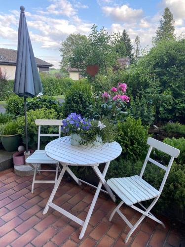 un tavolo e due sedie e un ombrellone e fiori di Ferien-/Monteurwohnung Linge (Marienheide) a Marienheide