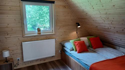 ein Schlafzimmer mit einem Bett in einer Holzhütte mit einem Fenster in der Unterkunft Chata Hanusi in Szczyrk
