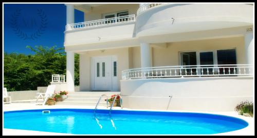a villa with a swimming pool in front of a house at Villa Bella By The Sea - Heated Pool, Jacuzzi, Sauna in Kožino