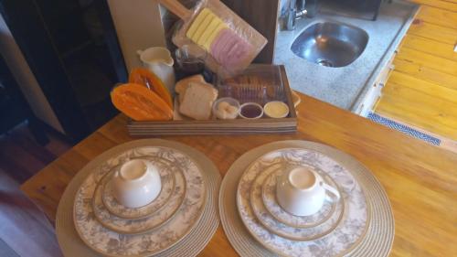 zwei Teller und Kerzen auf einem Holztisch in der Unterkunft Cabanas Capoeiras in Urubici