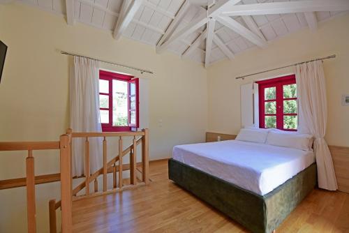 a bedroom with a bed and two windows at Douskos Porta Rossa in Hydra