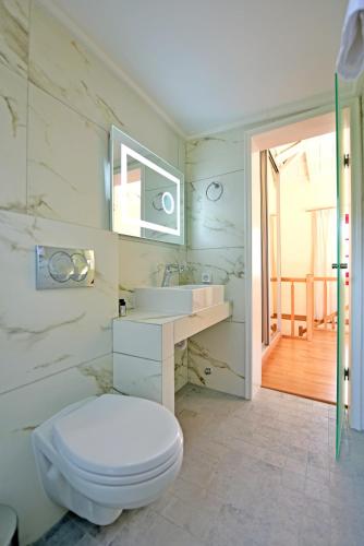 a white bathroom with a toilet and a sink at Douskos Porta Rossa in Hydra