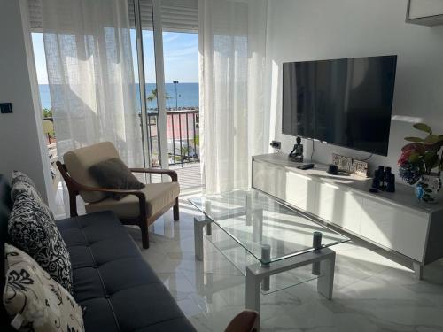 uma sala de estar com uma televisão e uma mesa de vidro em JAZMÍN DEL MAR em Torremolinos