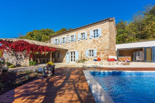 a stone house with a swimming pool in front of it at Villa Bell Aria in Grižane