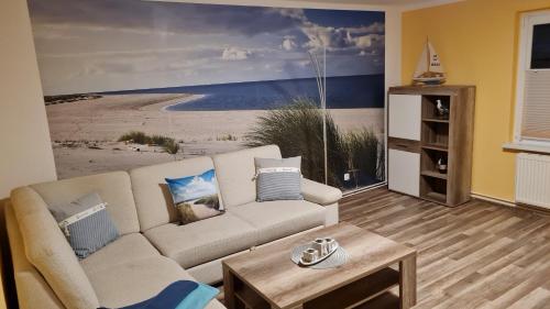 een woonkamer met een bank en een schilderij van een strand bij Ferienhaus Wiese und Meer in Zinnowitz
