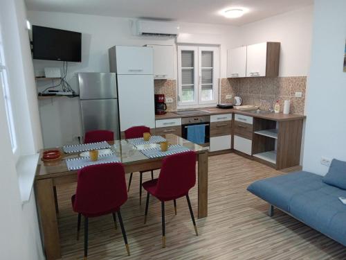 eine Küche mit einem Tisch und roten Stühlen in einem Zimmer in der Unterkunft Apartman Kastelanic in Brbinj