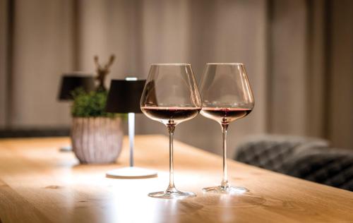 two glasses of wine sitting on a wooden table at Hotel Goldene Rose in Reutte