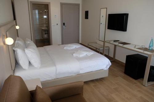 a bedroom with a white bed and a desk and a television at Fllad Resort & SPA Durres in Golem