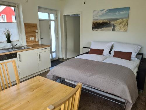 a bedroom with a bed and a kitchen with a table at Haus Hobbingshof Greetsiel in Greetsiel