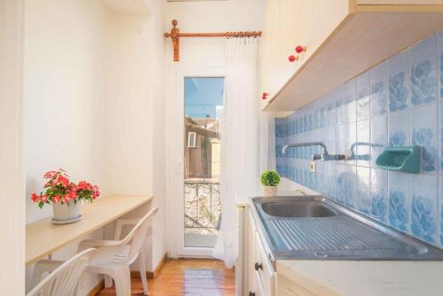 eine Küche mit einem Waschbecken und einer Theke mit einem Fenster in der Unterkunft Nona Marina's refurbished family home in Benitses