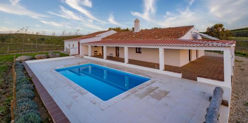 a villa with a swimming pool in front of a house at Monte do Pantaleão in Baleizão