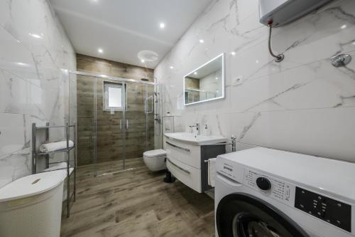 La salle de bains blanche est pourvue d'un lavabo et d'un lave-linge. dans l'établissement Luxury Apartment Maris, à Kaštela