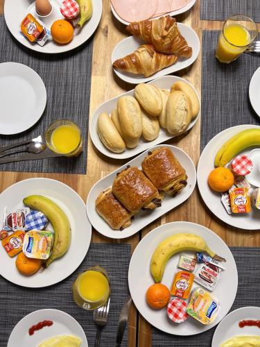 a table topped with plates of breakfast foods and fruit at La Maison Charentonneau in Maisons-Alfort