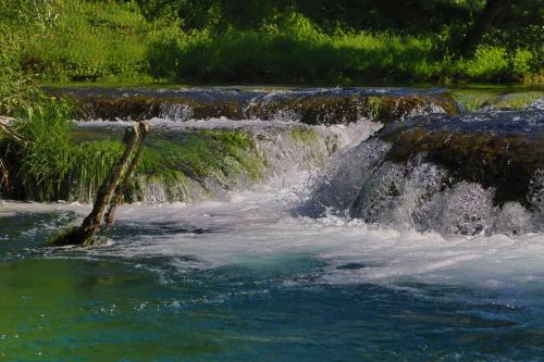 a stream of water rushing over rocks in a river at Apartment Green Lagoon in Bihać