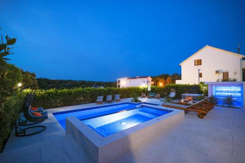 a backyard with a swimming pool at night at Villa Pino with Pool, Sauna & Jacuzzi in Petrcane
