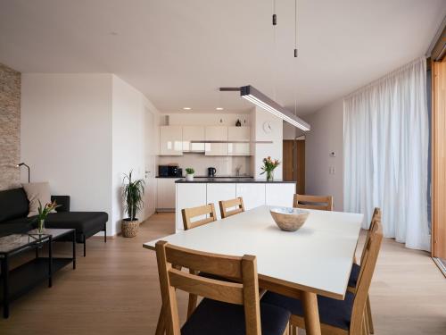 a kitchen and living room with a white table and chairs at Exklusives Ferienhaus - Direkt am Neusiedler See in Neusiedl am See