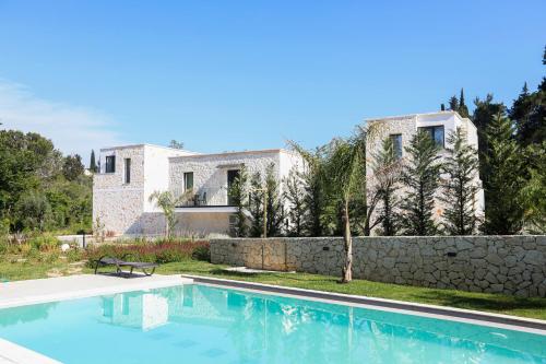 a villa with a swimming pool in front of a house at Rans Luxury Villas & Suites in Corfu with swimming pool in Gouvia