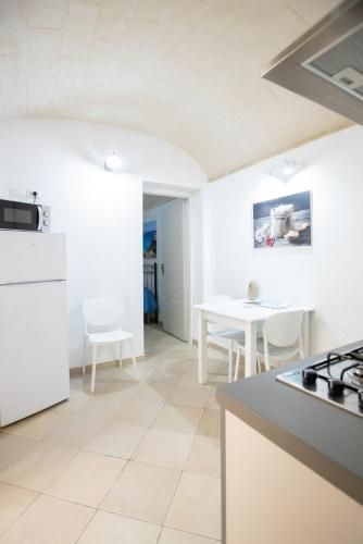 a kitchen with white appliances and a table with chairs at Fardella 250 in Trapani