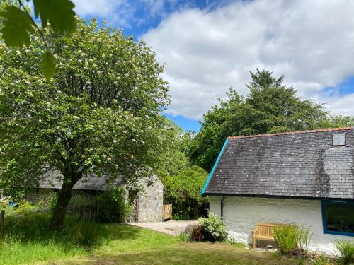 a building with a bench next to a tree at Woodland Cabins, Glencoe in Ballachulish