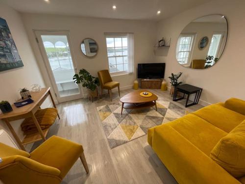 a living room with a yellow couch and a table at The Old Captains Lookout in Falmouth