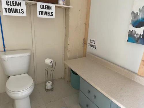 a bathroom with a toilet and signs on the wall at Dreamers Writing Farm, 3 Wooded Acres, Hepworth in Sauble Beach