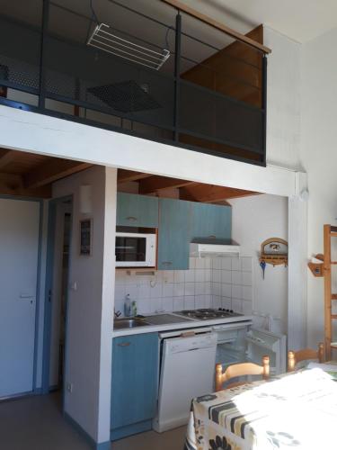 une cuisine avec des armoires bleues et un lit en mezzanine dans l'établissement Appart situé au sein d'une résidence à Barèges pour 4 à 6 personnes, 1 chambre, 1 mezzanine, à Barèges