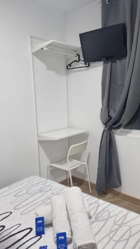 a room with a bed with a television and a chair at Hostal Vara Madrid in Madrid