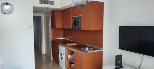 una cucina con armadi in legno, lavandino e TV di RESIDENCIAL LOS PATOS PLAYA a Benalmádena