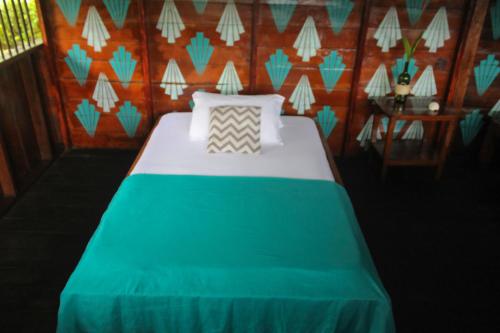 a bedroom with a bed with a green and white blanket at Refugio Mr Jerry Eco House in Bahía Solano