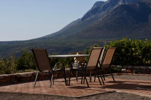 three chairs and a table with a view of a mountain at Sunset View Stone House, Areopoli Mani in Areopolis