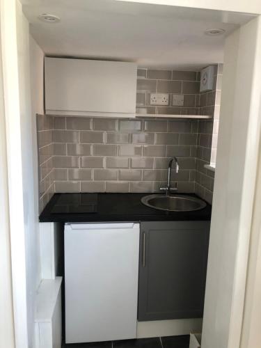 a small kitchen with a sink and a tile wall at Lovely Modern decorated 1 bed Studio in Newport