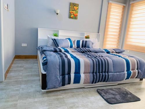 Schlafzimmer mit einem Bett mit blauer und weißer Bettwäsche in der Unterkunft Mus homes in Accra